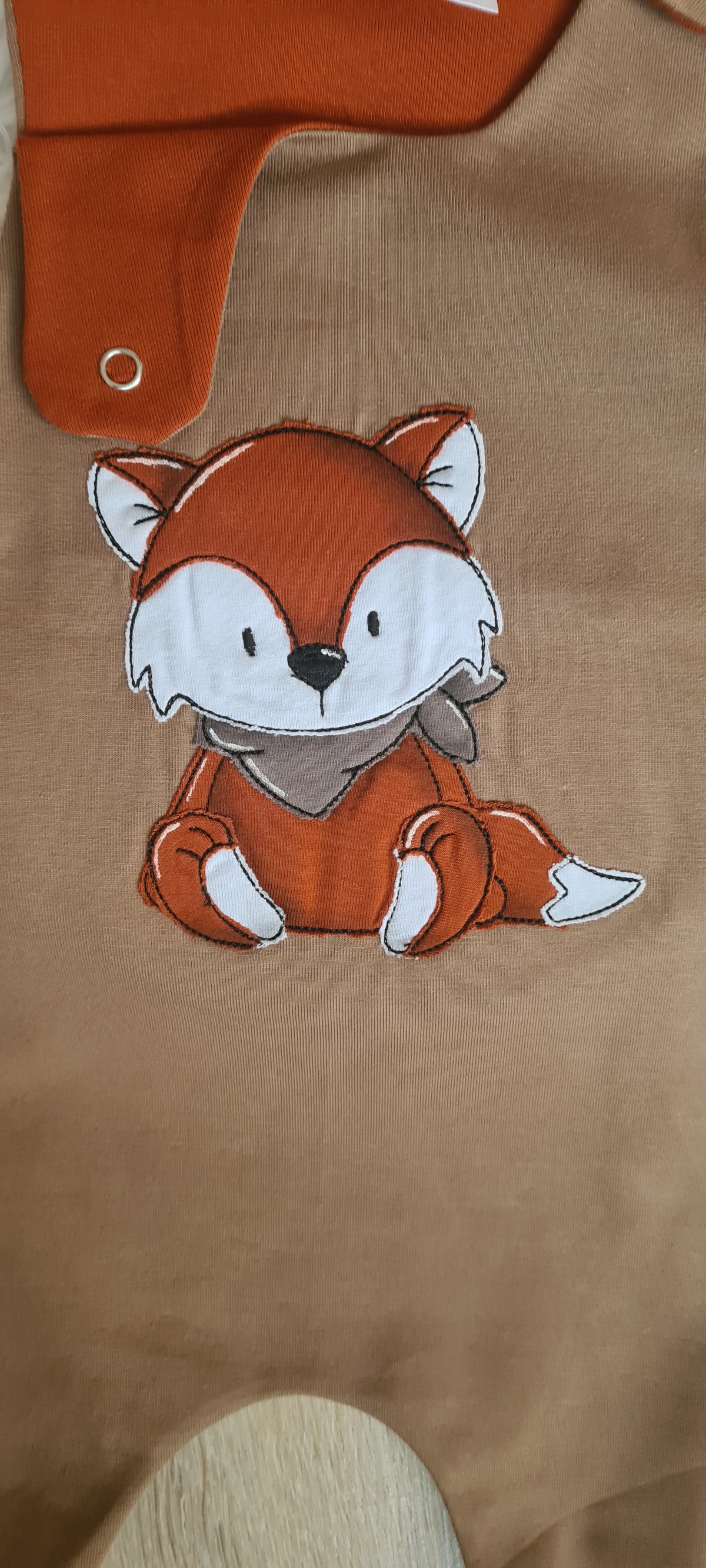 Nahaufnahme Fuchs-Stickerei auf braunem Baby-Strampler aus Jersey