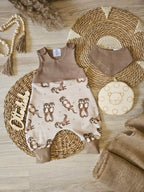 Baby Strampler "Otterliebe" Frontansicht – Otter-Allover French Terry in Sand mit braunem Jersey-Oberteil, handgenäht