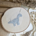 "Dino blüten" Bügelbild zum Aufbügeln – niedlicher grauer Dinosaurier mit Gänseblümchen im Aquarellstil auf Holzscheibe, handmade | Little Falili
