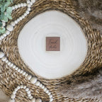 Braunes PU-Kunstlederlabel mit dem Schriftzug „Frechdachs“ auf einer hellen Holzscheibe im natürlichen Boho-Stil.