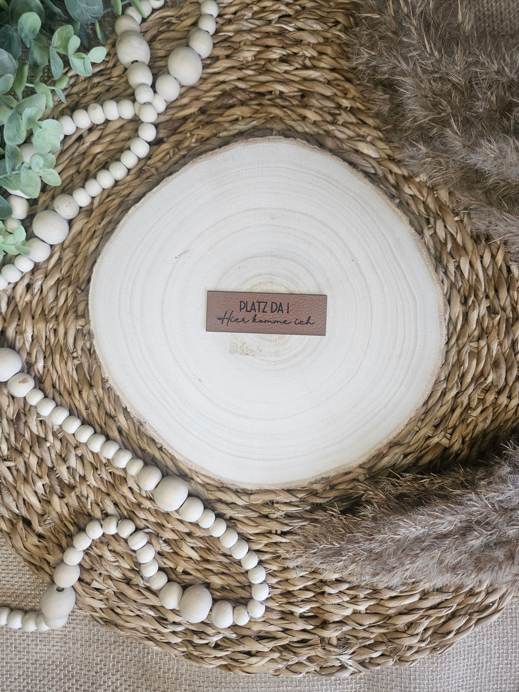 Braunes PU-Kunstlederlabel mit dem Schriftzug „Platz da“ auf einer hellen Holzscheibe im natürlichen Boho-Stil.