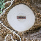 Braunes PU-Kunstlederlabel mit dem Schriftzug „Einzigartig“  auf einer hellen Holzscheibe im natürlichen Boho-Stil.