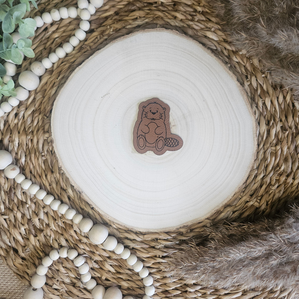 Braunes PU-Kunstlederlabel mit  „Biber“  auf einer hellen Holzscheibe im natürlichen Boho-Stil.