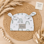 Handgemachter Babymützer mit liebevollem RegenbogenMuster im Boho-Mockup auf hellem Holzuntergrund