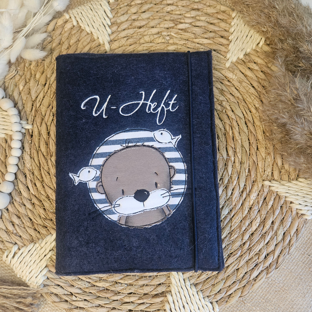 Dunkelblaue U-Heft-Hülle aus Filz mit Otter- und Fisch-Applikation sowie Schriftzug U-Heft